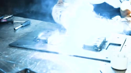 Welder at Work. Worker Welds Metal Parts. Welding Process, Sparks, Flame, Smoke.