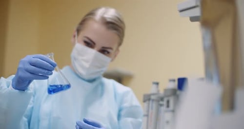 Young Adult Scientist Examining Blue Liquid in Flask