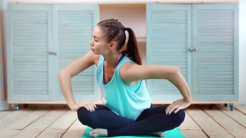 Young Pilates Woman Sitting on Mat Stretching After Training at Gym Putting Hands on Legs Full Shot