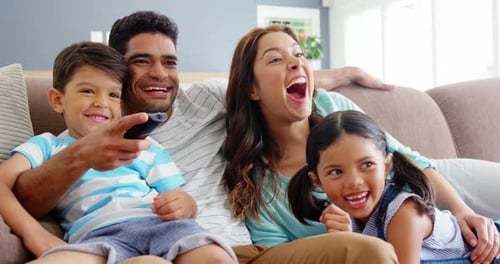 Family Laughing and Watching TV Together at Home