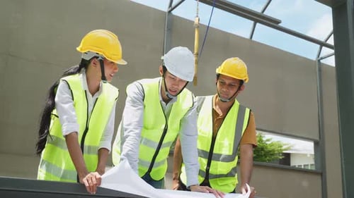 Engineers Collaborating Over Blueprints at Construction Site
