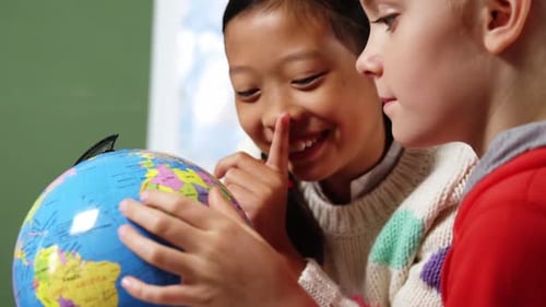 Schulkinder schauen sich den Globus im Klassenzimmer der Schule an