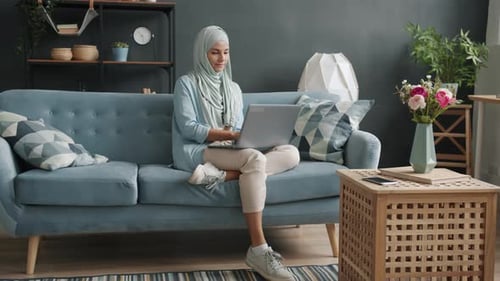Woman Working on Laptop Sitting on Blue Couch