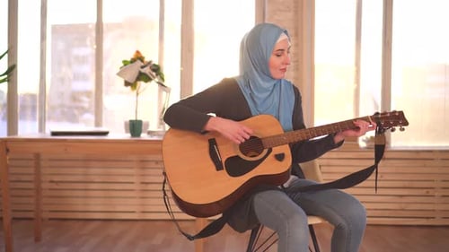 Young Woman Plays Acoustic Guitar in Bright Room