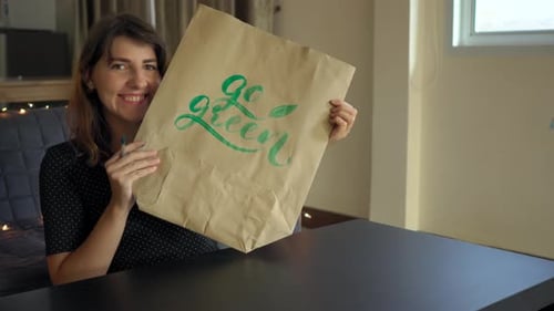 Primer plano de una joven calígrafa escribiendo en una bolsa de papel usando la técnica de letras.
Ella