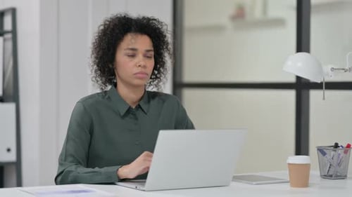 Woman Working at Desk Coughs into Elbow