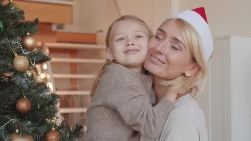Mother and Daughter Hugging By Christmas Tree