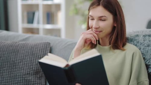Woman Enjoys Reading Book on Couch at Home