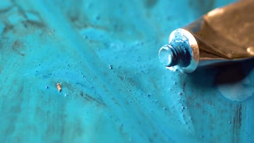 El color azul sale del tubo. Tubo de color abierto en el suelo. Pincel de pintura sobre una superficie azul