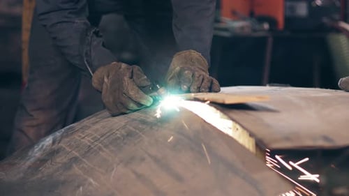 Workman's Hands Cutting Metal with Torch Using Wood Plank to Adjust an Even Line