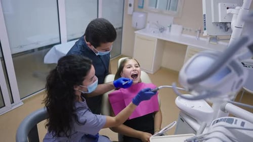 Dentist Examining a Young Girl's Teeth in Clinic