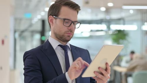 Focused Businessman Using Tablet in Modern Office