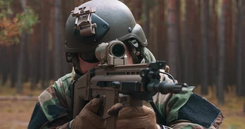 A Soldier in a Special Military Uniform with a Helmet on His Head and with a Sniper Rifle in the