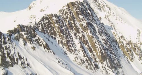Aerial helicopter shot around mountainside with clouds, tilt up to reveal valley with many small riv