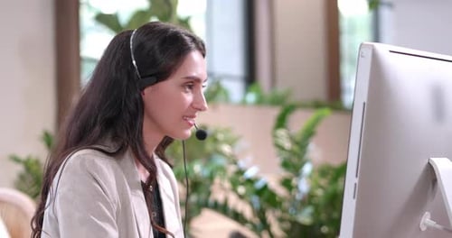 Geschäftsfrau mit Headset arbeitet im Büro mit Computer