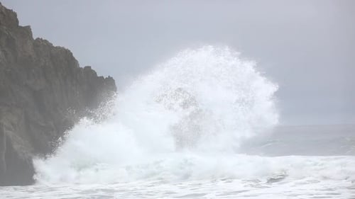Powerful Waves Crashing Against Rocky Coastline on Overcast Day