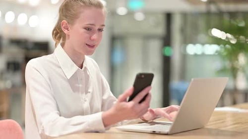 Woman Works on Laptop and Phone in Office