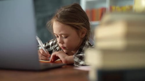 Closeup of Serious Primary Child School Girl Doing Homework Writing Notes in Paper Notebook and