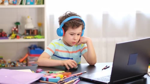 Focused Boy Using Laptop with Headphones at Home