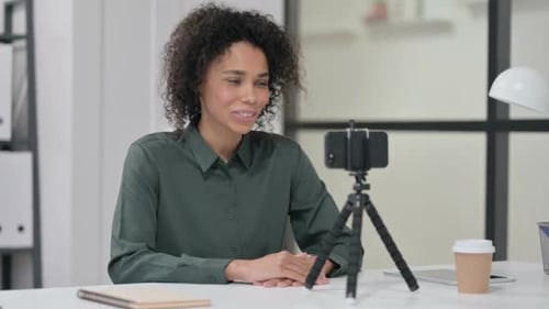 Woman Speaking into Smartphone on Tripod at Desk