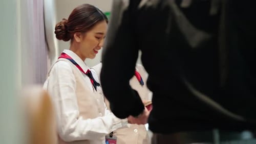Une agente de bord 4K vérifie la carte d'embarquement des passagers dans un avion.