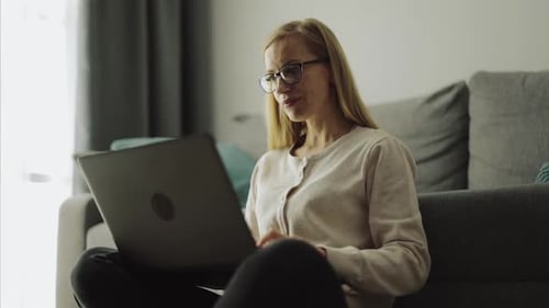 Woman with Laptop Sitting on Floor in Home