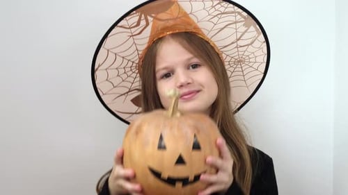 Girl Holding Halloween Pumpkin Wearing a Witch Hat
