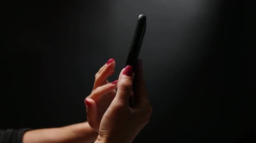 Hands Using a Cell Phone on Black Background