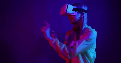 Young Asian woman playing metaverse virtual reality digital technology game with VR goggle.