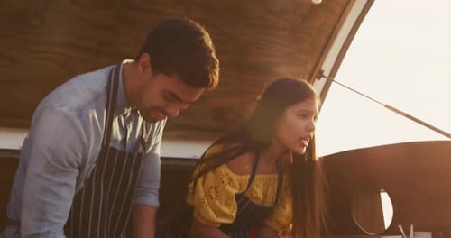 Joven pareja cocinando juntos en un camión de comida