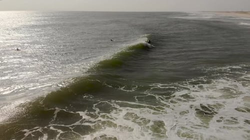 Epic drone tracking shot of surfer riding a wave.