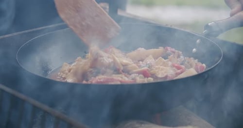 Close Up Fresh Vegetables Are Cooked in a Pan on Open Fire in the Open Air. Slow Motion