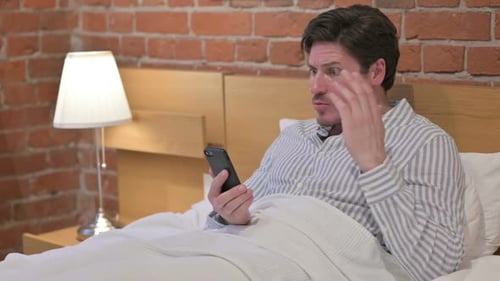 Man in Bed Shocked by Smartphone