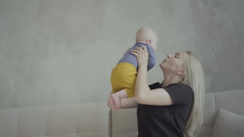 Happy Mother Holds Baby High in Home