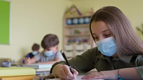 Video of school children and teacher in classroom during a pandemic.