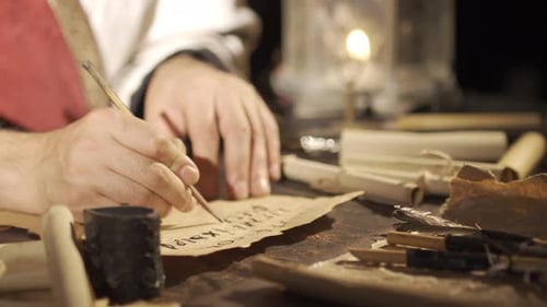Person writing on old paper with quill