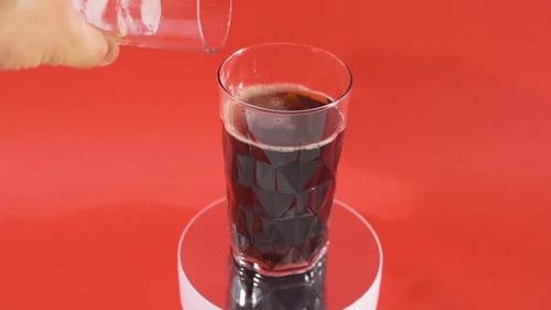 Iced Drink Poured into Glass on Red Surface