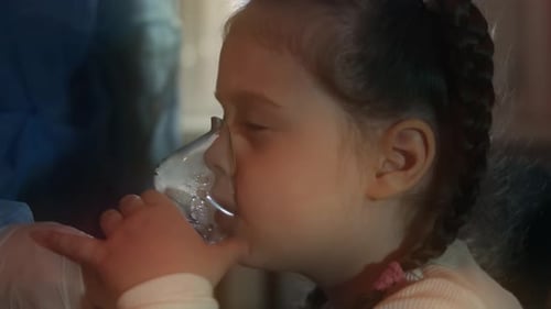 Hermosa niña inhala usando un inhalador compresor en el hospital