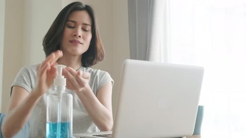 Woman Uses Hand Sanitizer While Working at Home