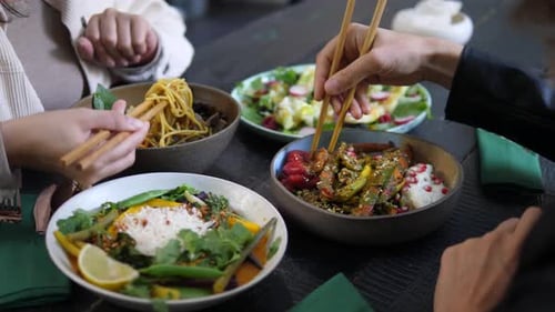 Lunch Break at Oriental Cuisine Restaurant. Meals Served in Colorful Bowls on Black Wooden Table.