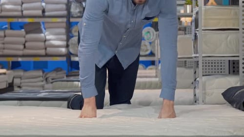 Man Choosing Orthopedic Mattress Lying on a New Bed at the Store