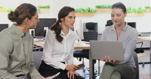 Team Discussing Ideas Using Laptop in Modern Office