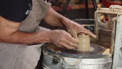 Un potier âgé utilise le tour de potier et fixe des parois minces à la poterie