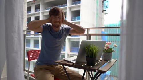 Man Covering Ears at Noisy Balcony Workspace