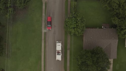 A fire engine slowly passes a red car on a flash flooded street.