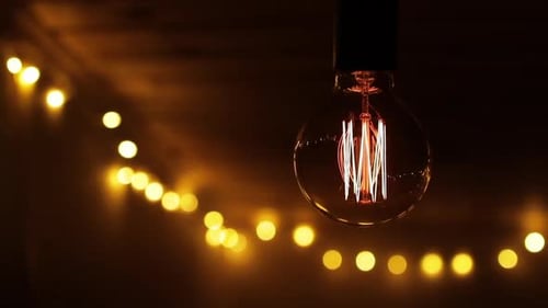 Retro Light Bulb Flickering on a Wooden Ceiling Close Up