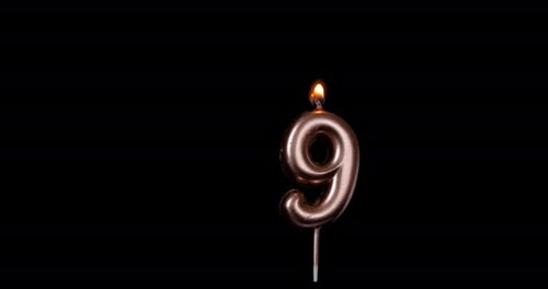 Burning Metallic Number Nine Candle on Black Background