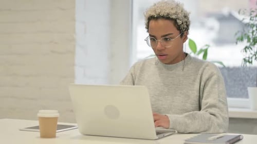 African Woman Coughing While Using Laptop in Office