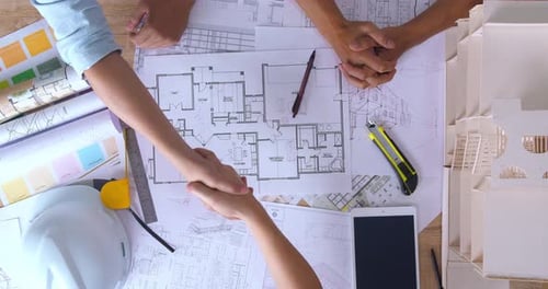 Top View Of Architect And The Engineering Contractor Shaking Hands On Building Project