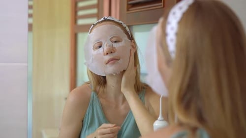 A Young Woman Puts on a Cosmetical Face Mask. Skincare Concept